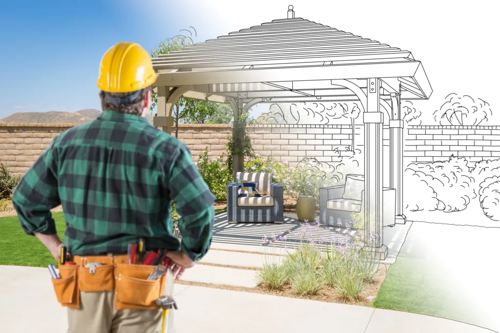 Contractor planning backyard pavilion installation with half-drawn design and half-completed outdoor living space
