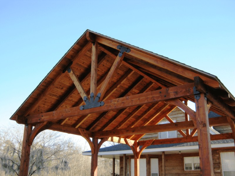 Timber frame pavilion with exposed wood trusses and black metal brackets